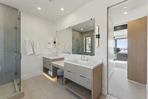 Bathroom featuring double vanity, a shower stall, recessed lighting, and light tile patterned floors