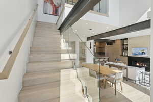 Stairs with a fireplace, recessed lighting, wood finished floors, and a high ceiling