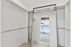 Walk in closet featuring light colored carpet