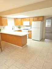 Kitchen featuring new white appliances, light countertops, and new paint, and a new tap, a peninsula