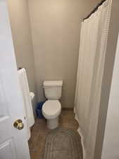 Bathroom with a shower with shower curtain and light tile patterned floors