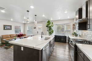 Kitchen with dark wood finish cabinets, stainless steel appliances, marble countertops, LVP floors, and decorative backsplash