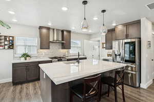 Kitchen with dark wood finish cabinets, stainless steel appliances, a huge island, pendants, and recessed lighting