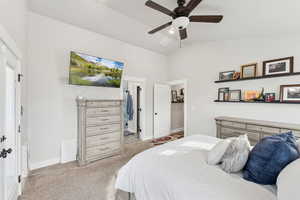 Primary Bedroom with vaulted ceiling, light colored carpet, and ceiling fan