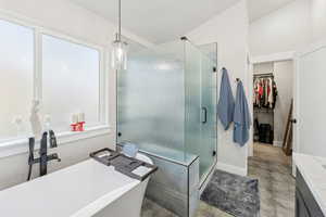 Primary ensuite featuring double vanity, a soaking tub, separate shower, and walk-in closet