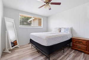 Bedroom featuring ceiling fan, light wood-type flooring, and a textured ceiling