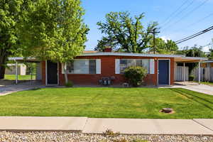 View of front facade featuring a carport, driveway, a chimney, and a front yard