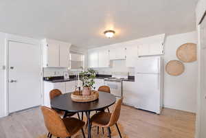 Kitchen featuring white appliances, dark countertops, and white cabinets