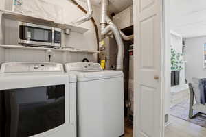 Laundry area with light wood finished floors, separate washer and dryer, and heating unit