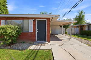 View of exterior entry with an attached carport, driveway, and brick siding
