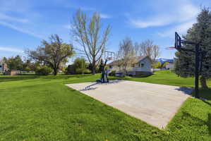 View of basketball court featuring a yard and basketball court