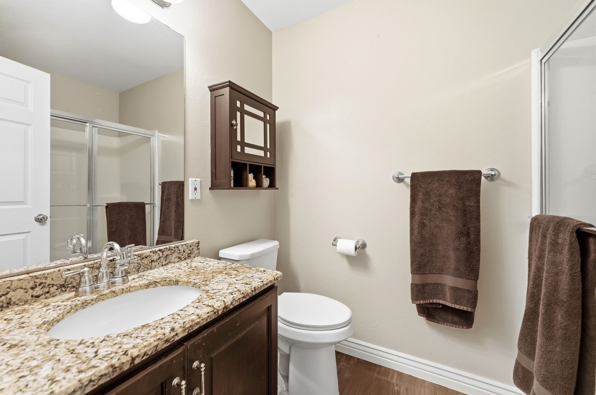 Bathroom with vanity, a shower stall, and dark wood-style flooring