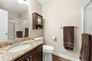 Bathroom with vanity, a shower stall, and dark wood-style flooring