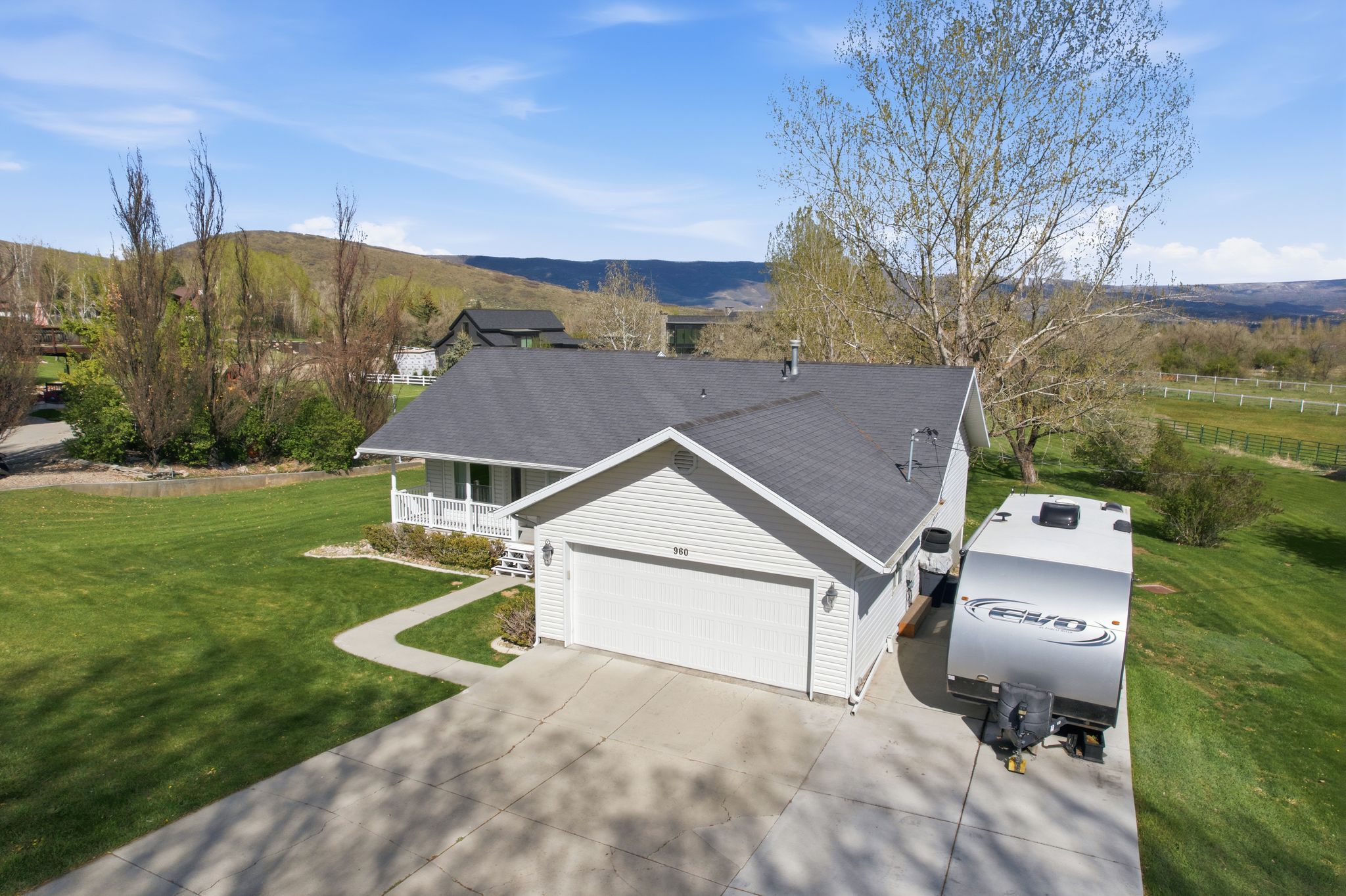 View of front of house featuring a front lawn, driveway, covered porch, a garage, and a mountain view
