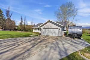 View of side of property with a lawn, an attached garage, and concrete driveway