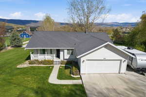 Single story home with a porch, a mountain view, roof with shingles, a garage, and driveway