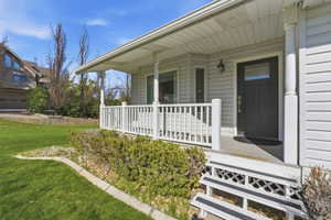 View of exterior entry with a porch and a yard