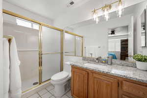 Full bathroom with vanity, a stall shower, light tile patterned floors, ensuite bath, and a ceiling fan