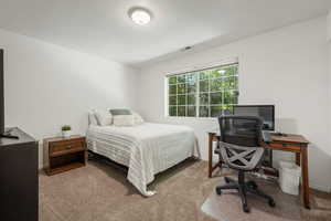 Carpeted bedroom featuring a desk and baseboards