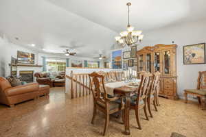 Dining space with a chandelier, vaulted ceiling, and a glass covered fireplace