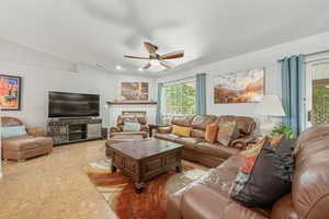 Living area featuring ceiling fan, a brick fireplace, and vaulted ceiling