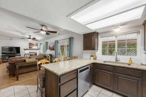 Kitchen featuring dark wood finish cabinetry, a peninsula, light stone counters, a kitchen breakfast bar, and a fireplace