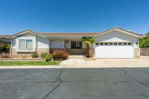 Ranch-style home featuring covered porch, a tiled roof, brick siding, and a garage