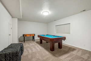 Recreation room with a textured ceiling, billiards table, and light carpet