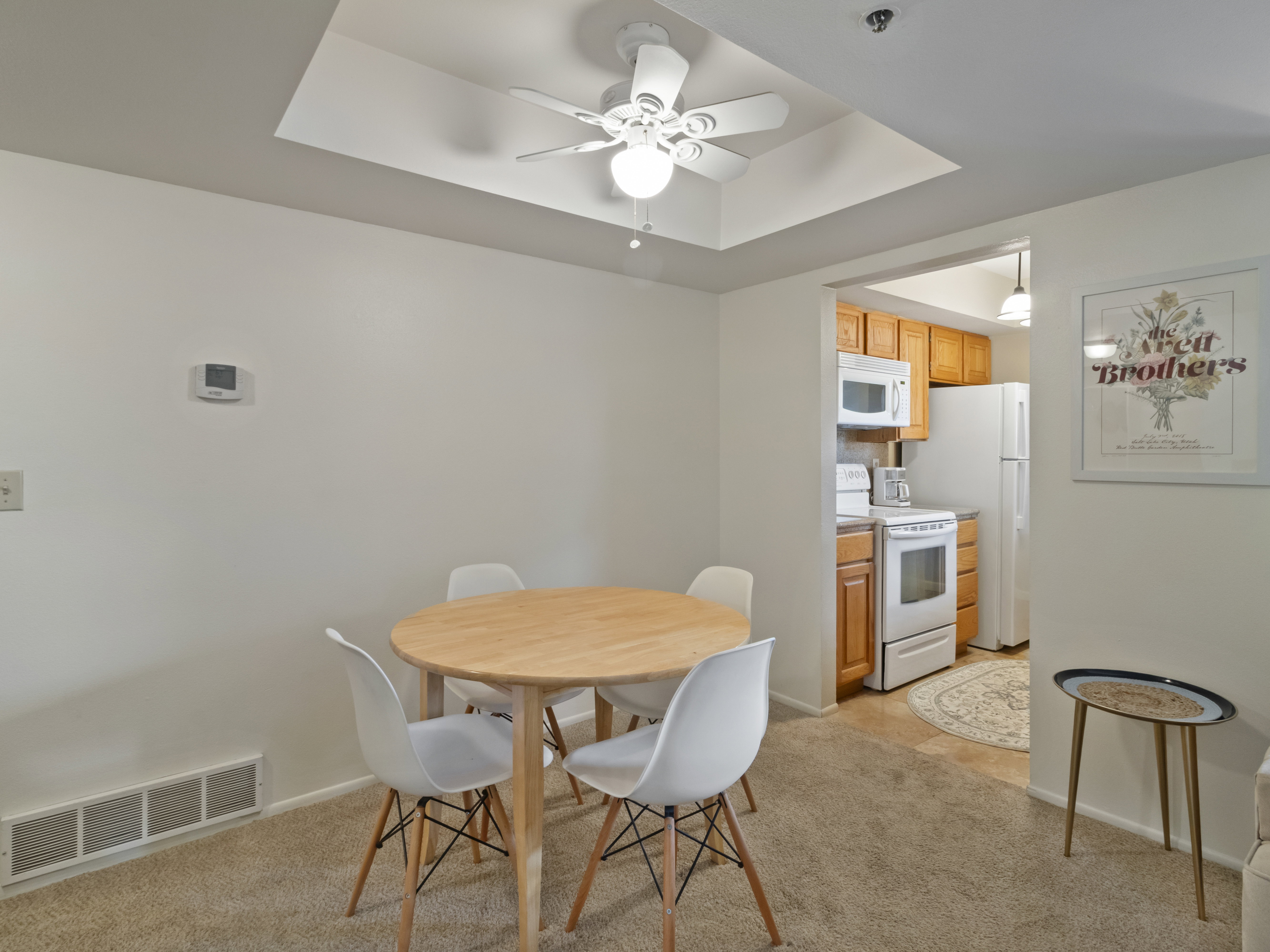 Dining area featuring a ceiling fan, a raised ceiling, and light colored carpet