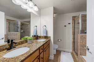 Full bathroom featuring double vanity, a stall shower, and light tile patterned floors