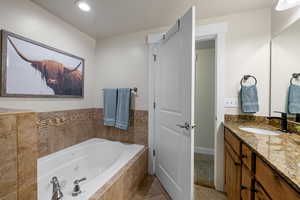 Bathroom with vanity, a whirlpool tub, and light tile patterned flooring