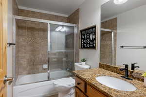 Bathroom featuring vanity and bath / shower combo with glass door