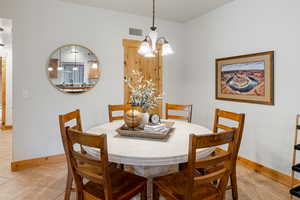 Dining room with light tile patterned floors and a chandelier