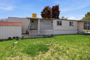 Rear view of house featuring entry steps, a yard, and a shed
