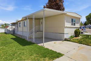 View of front of property featuring a front yard, an attached carport, driveway, and a storage unit