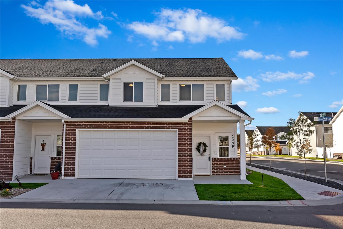 Traditional-style house featuring brick siding, concrete driveway, an attached garage, and roof with shingles