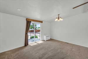 Carpeted empty room with a chandelier, a textured ceiling, and ceiling fan