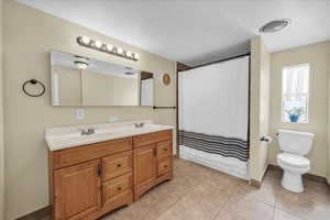 Bathroom with double vanity, a shower with curtain, and light tile patterned floors