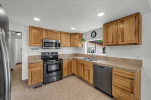 Kitchen with stainless steel appliances, recessed lighting, tile counters, and light tile patterned floors