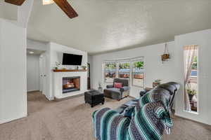 Living room featuring a ceiling fan, a fireplace, and carpet