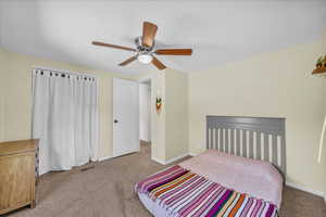 Carpeted bedroom with ceiling fan and baseboards