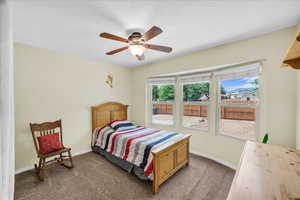 Bedroom with dark carpet, a ceiling fan, and a textured ceiling