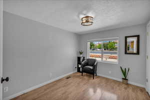 Living area featuring light wood-style floors and a textured ceiling