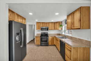 Kitchen with stainless steel appliances, recessed lighting, light countertops, light tile patterned floors, and a textured ceiling