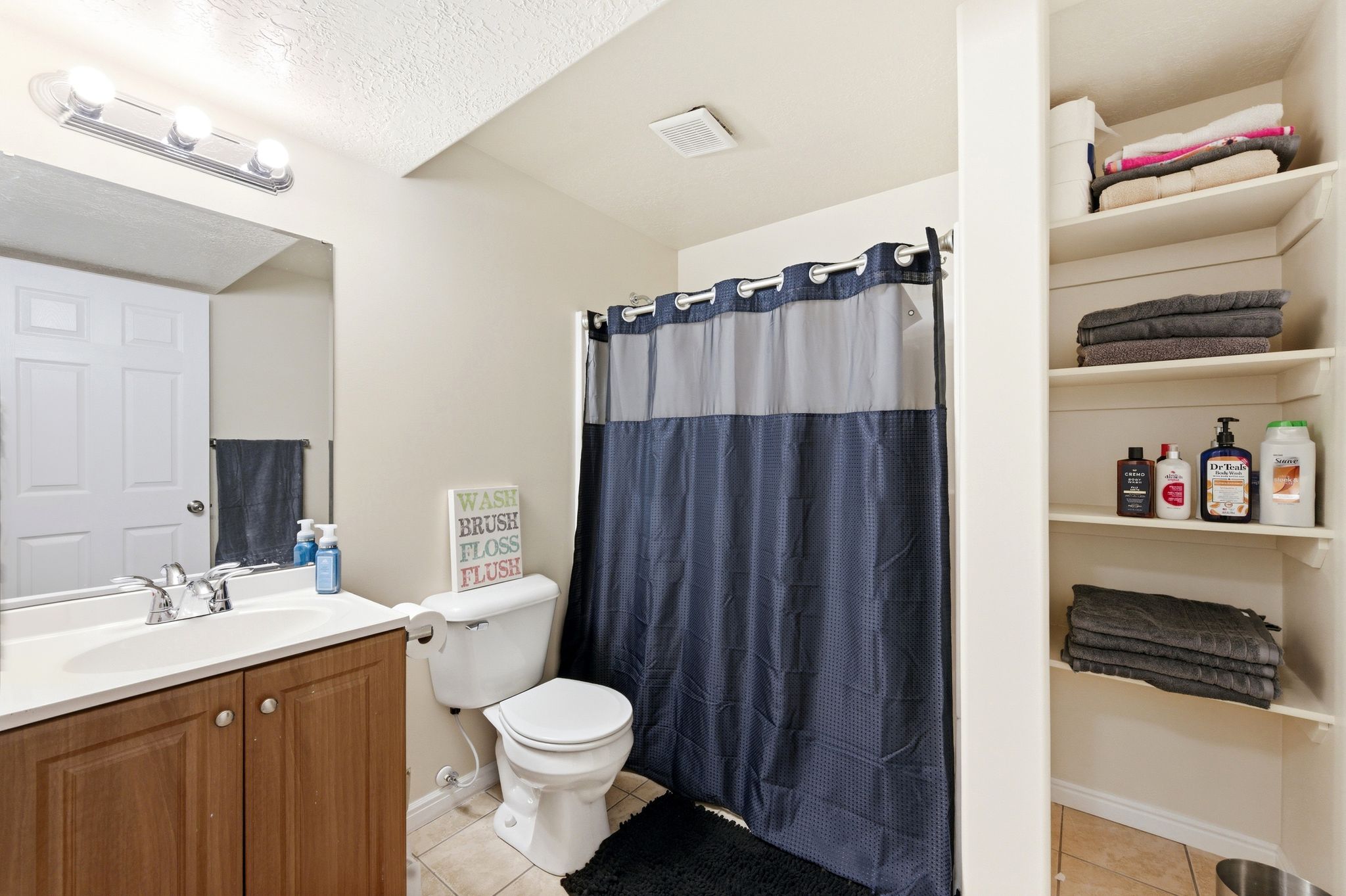 Bathroom featuring curtained shower, vanity, and light tile patterned floors