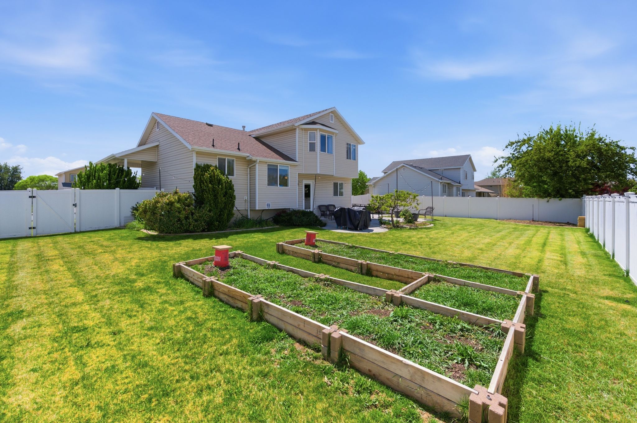 Rear view of house with a gate, a fenced backyard, and a vegetable garden