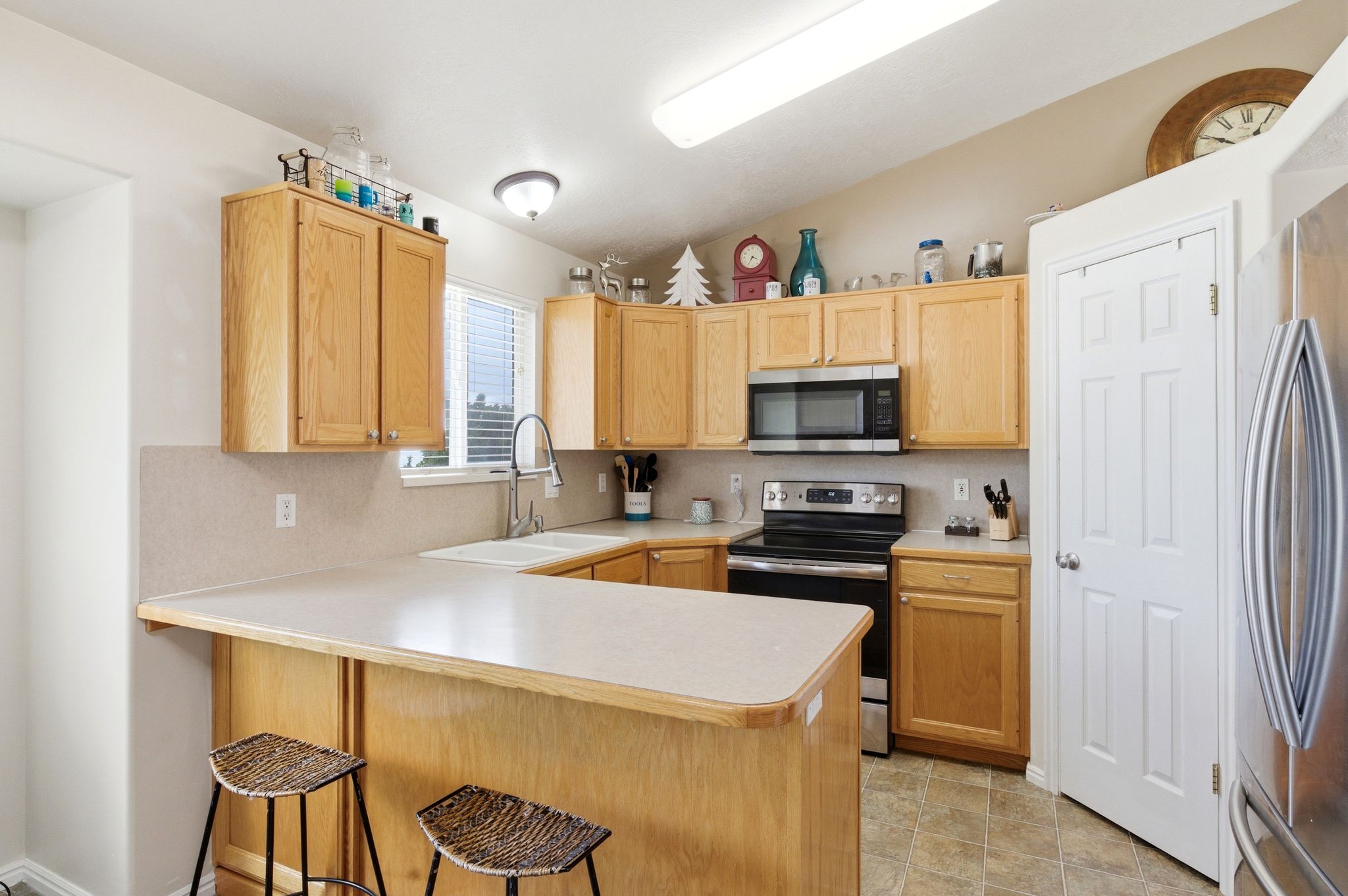 Kitchen with light countertops, stainless steel appliances, light wood finish cabinets, lofted ceiling, and a peninsula