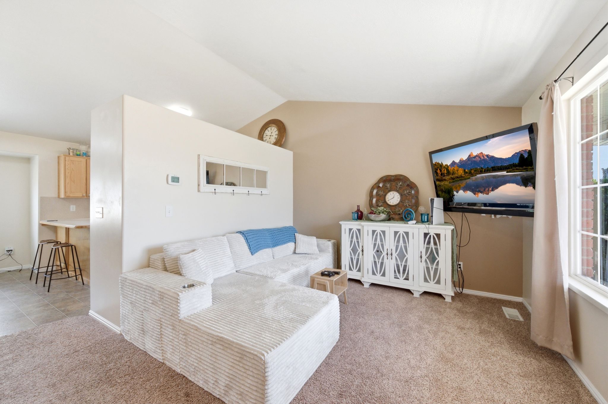 Living room featuring light colored carpet and vaulted ceiling