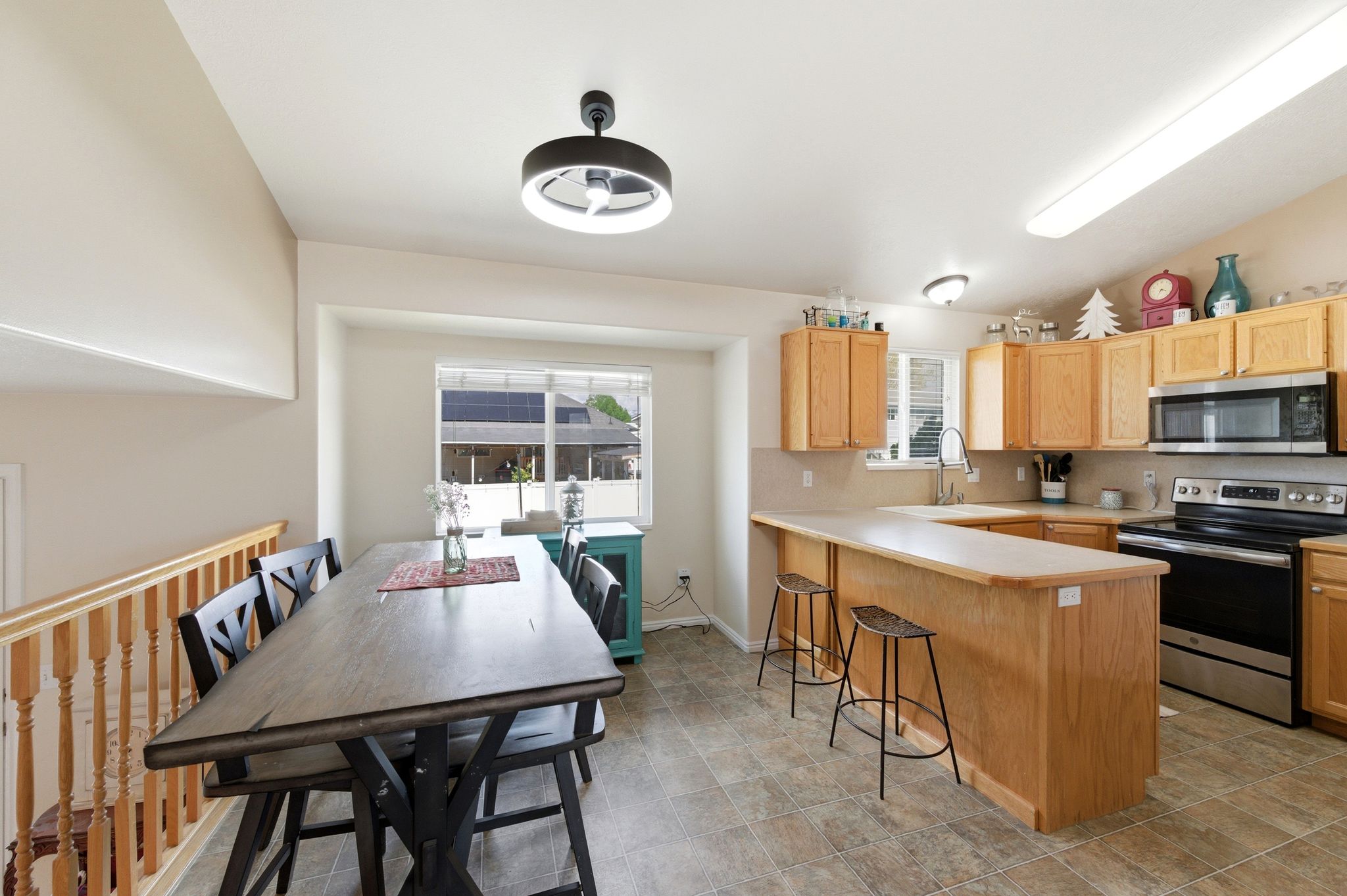 Kitchen with stainless steel appliances, light countertops, light wood finish cabinetry, a peninsula, and a breakfast bar
