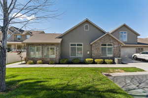 Craftsman-style home featuring stucco siding, stone siding, a garage, and driveway